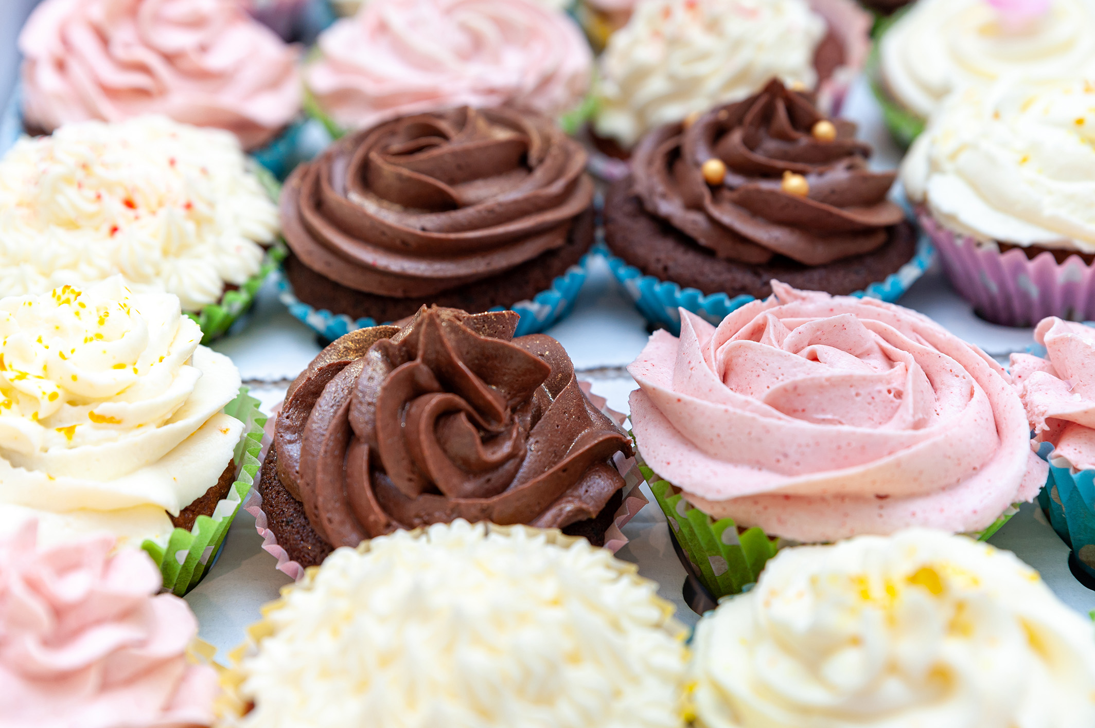 Home baked cupcakes beautifully decorated with buttercream on top placed on wooden table.
