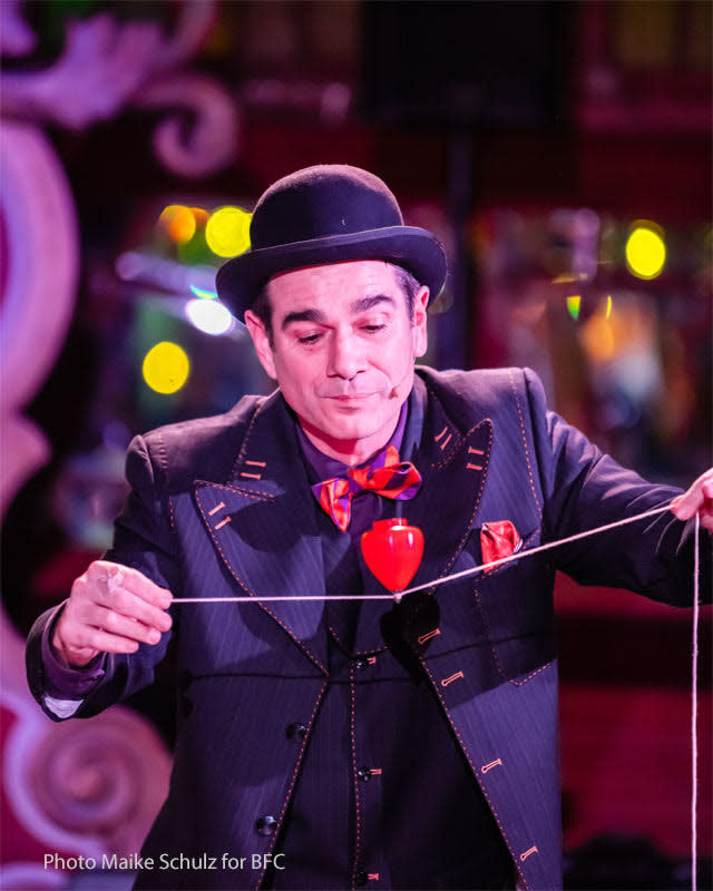 A Bindlestiff Family Cirkus performer executes a trick with a string and a spinning top.