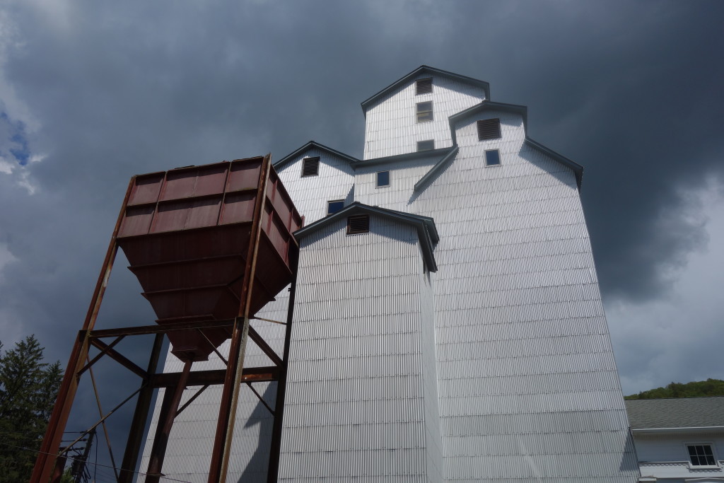The Maxon Mills art gallery in Wassaic, a repurposed seven-story wooden grain elevator along the train tracks, with dark clouds looming overhead.