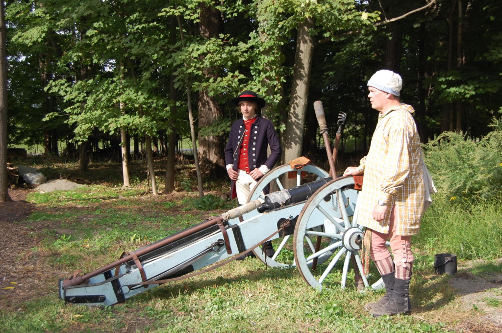 Two Revolutionary War reenactors prepare to fire a cannon.
