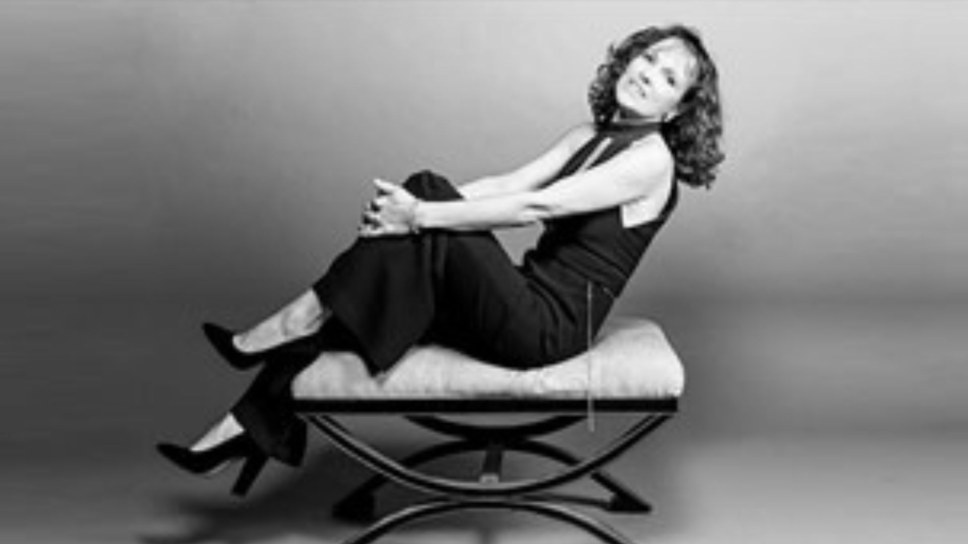 Black-and-white pgoto of world-renowned vocalist and performer Helen Welch relaxing on a sofa.