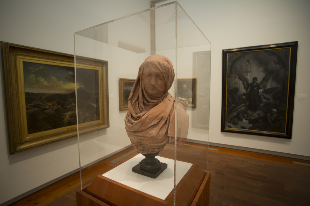 A statue and paintings in an art museum.