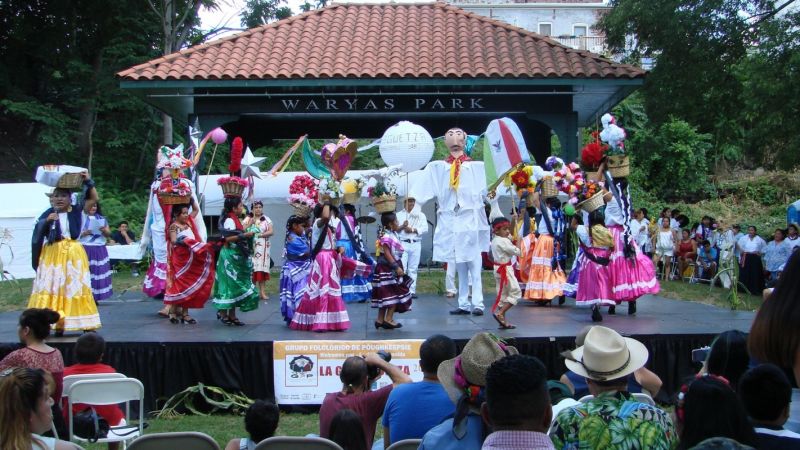 Dancers in colorful costumes perform on stage at Waryas Park in Poughkeepsie during La Guelaguetza.