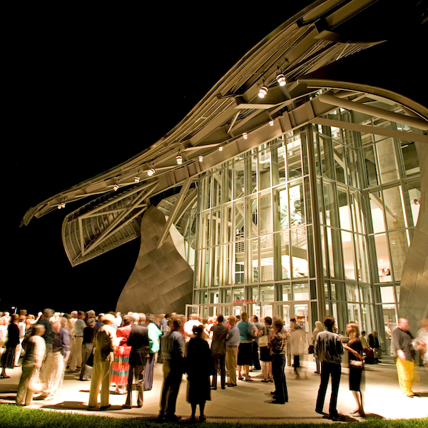 Crowd gathered at the entrance to the iconic Fisher Center at Bard College at night.