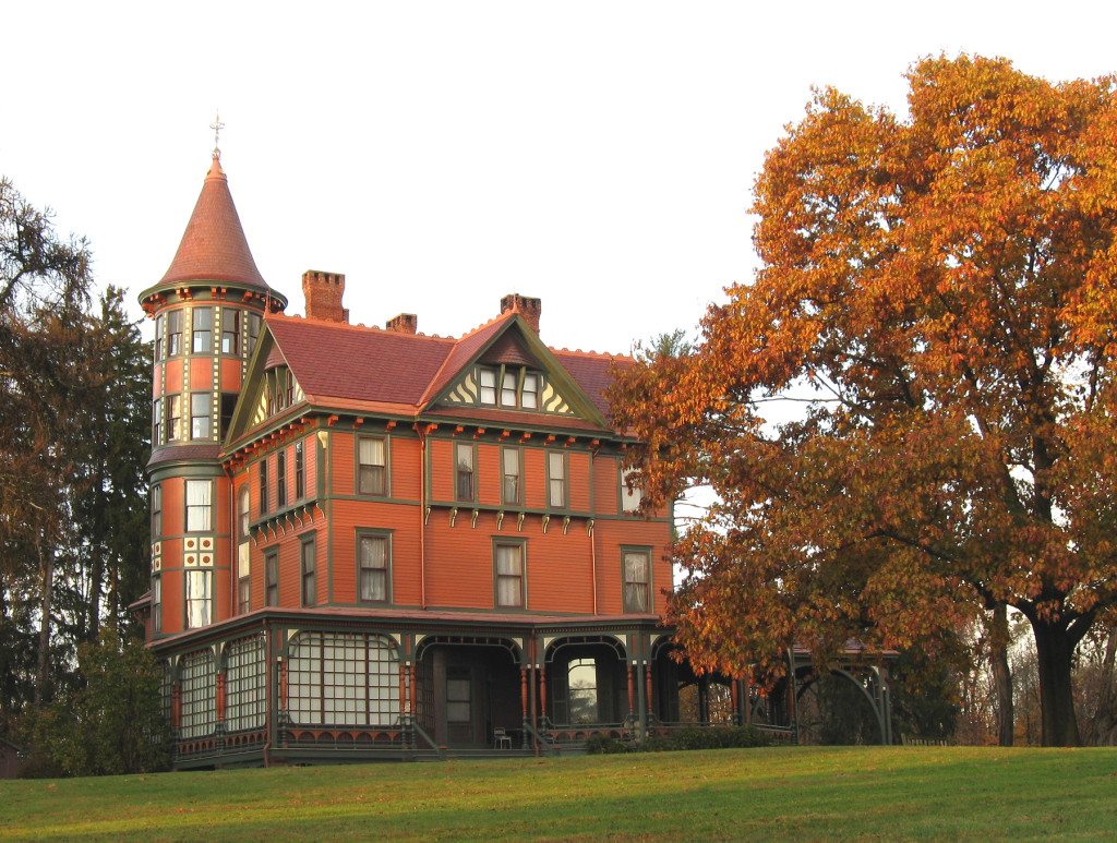 An exterior photo of the mansion at Wilderstein Historic Site with the nearby trees ablaze in autumn colors.