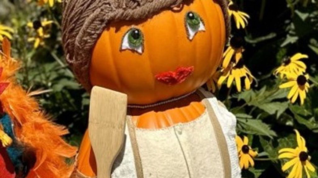 A bright orange pumpkin is decorated to look like a little girl with brown yarn for hair, a tan apron and a wooden cooking spoon during the Harvest Hunt at Locust Grove Estate in Poughkeepsie.