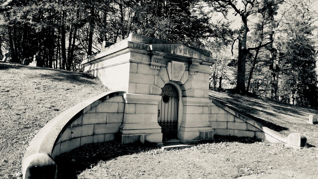 A black-and-white photo of a stone mausoleum that has been build into a hillside at the Wappingers Rural Cemetery.