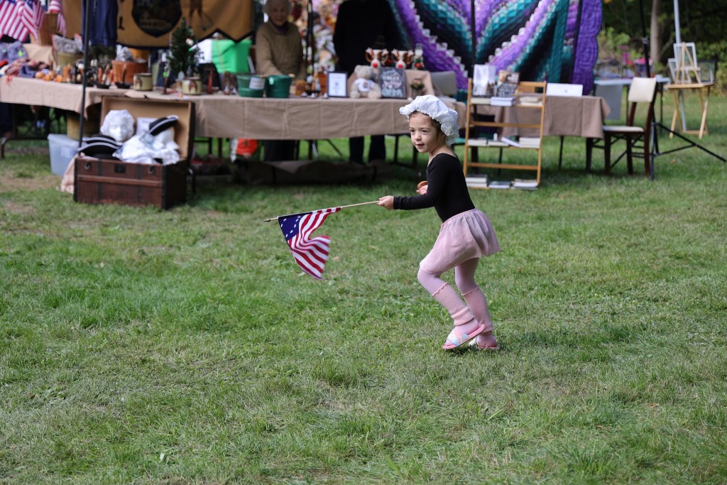 A little girl in a bonnet waves a small American Flag at the Van Wyck Homestead Museum in Fishkill.