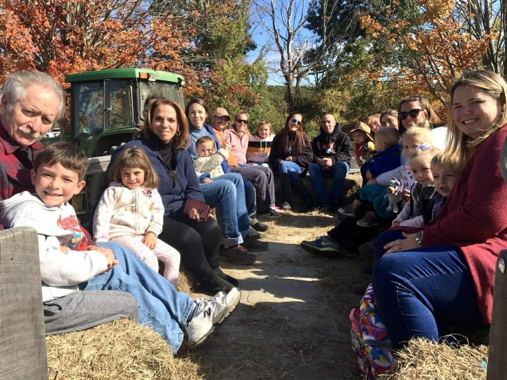 Several families with small children sit on bales of hay in a wagon being pulled by a green tractor at Soukup Farms in Dover Plains.