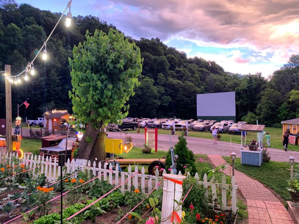 A view from afar of the movie screen and the cars parked in front of it at dusk before the start of a double feature at Four Brothers Drive-In Theatre in Amenia.