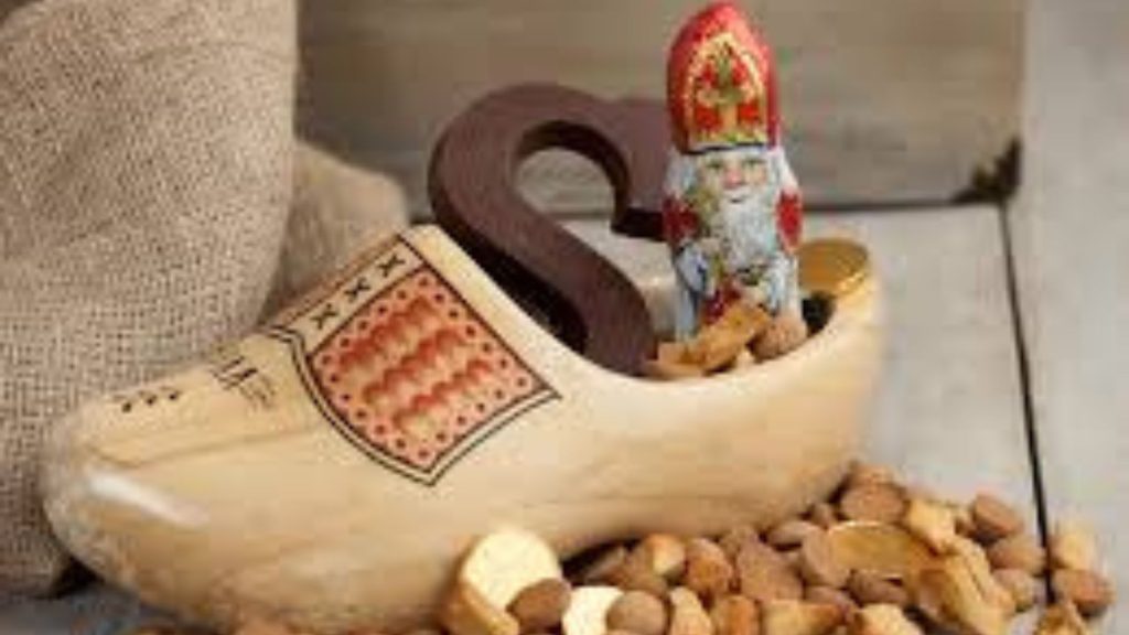 A wooden shoe is filled with nuts and a Sinterklaas figurine.