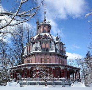 The pink and green Octagon House covered in snow.
