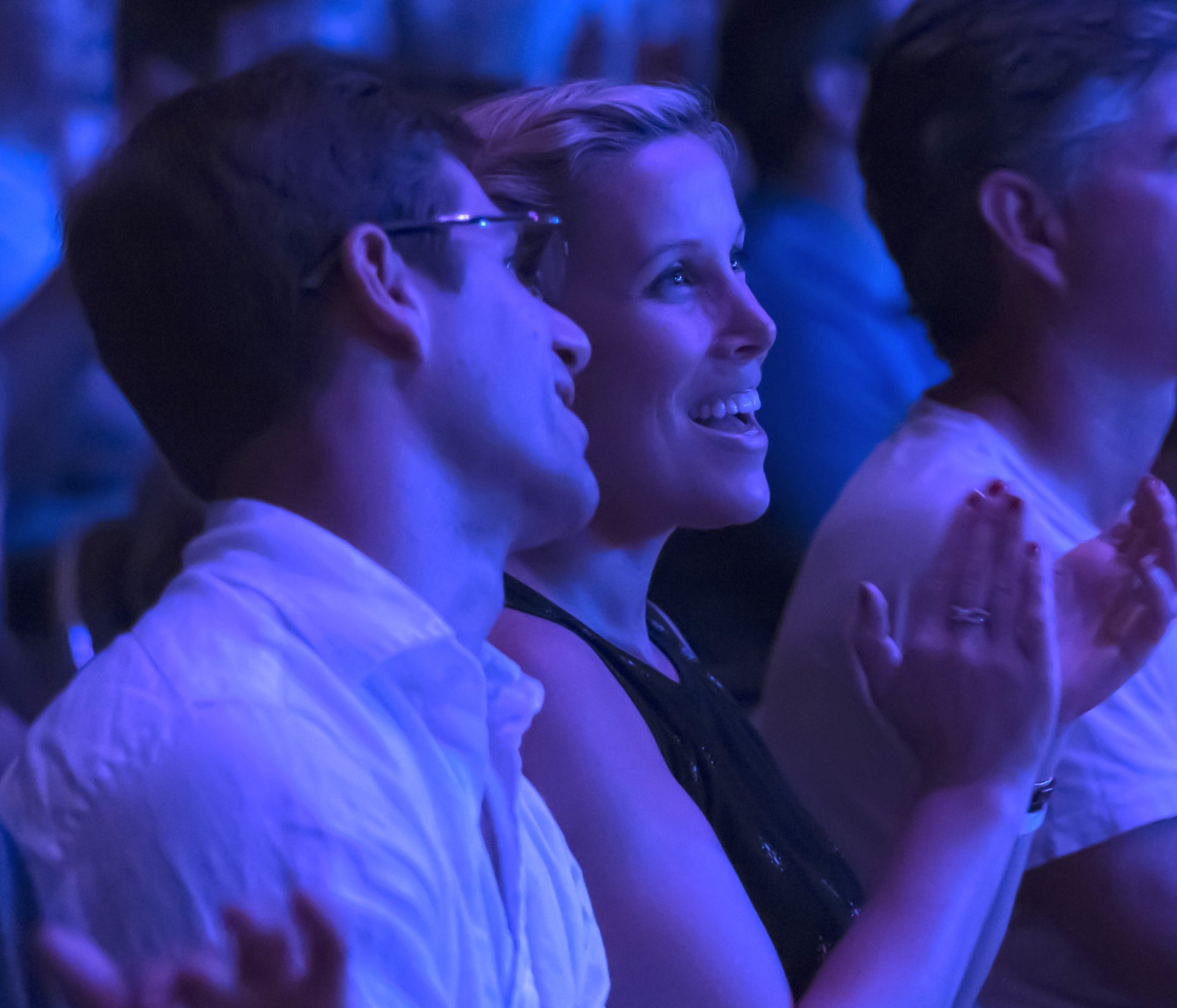 A couple sits together laughing and clapping.