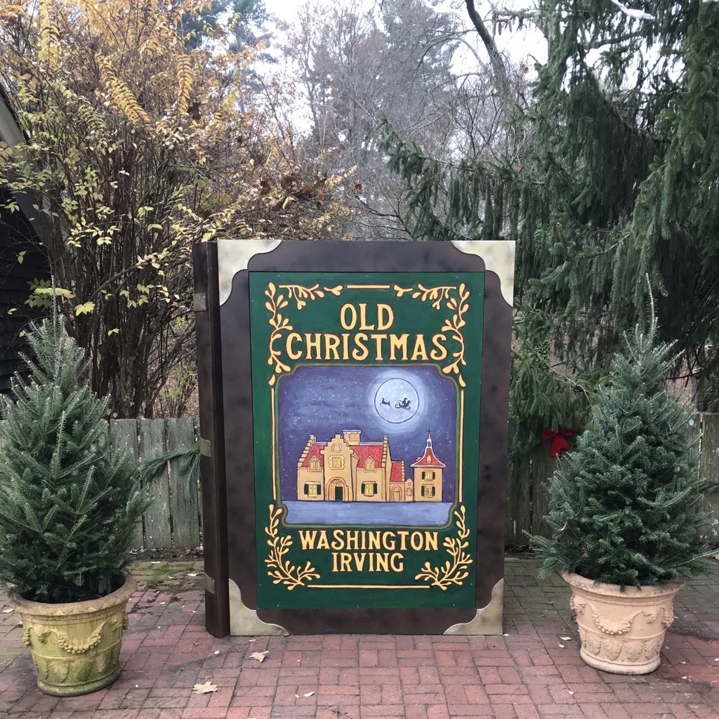 A sign, surrounded by evergreen trees, says "Old Christmas."