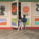 Two children pull open the door of the Westchester Children's Museum.