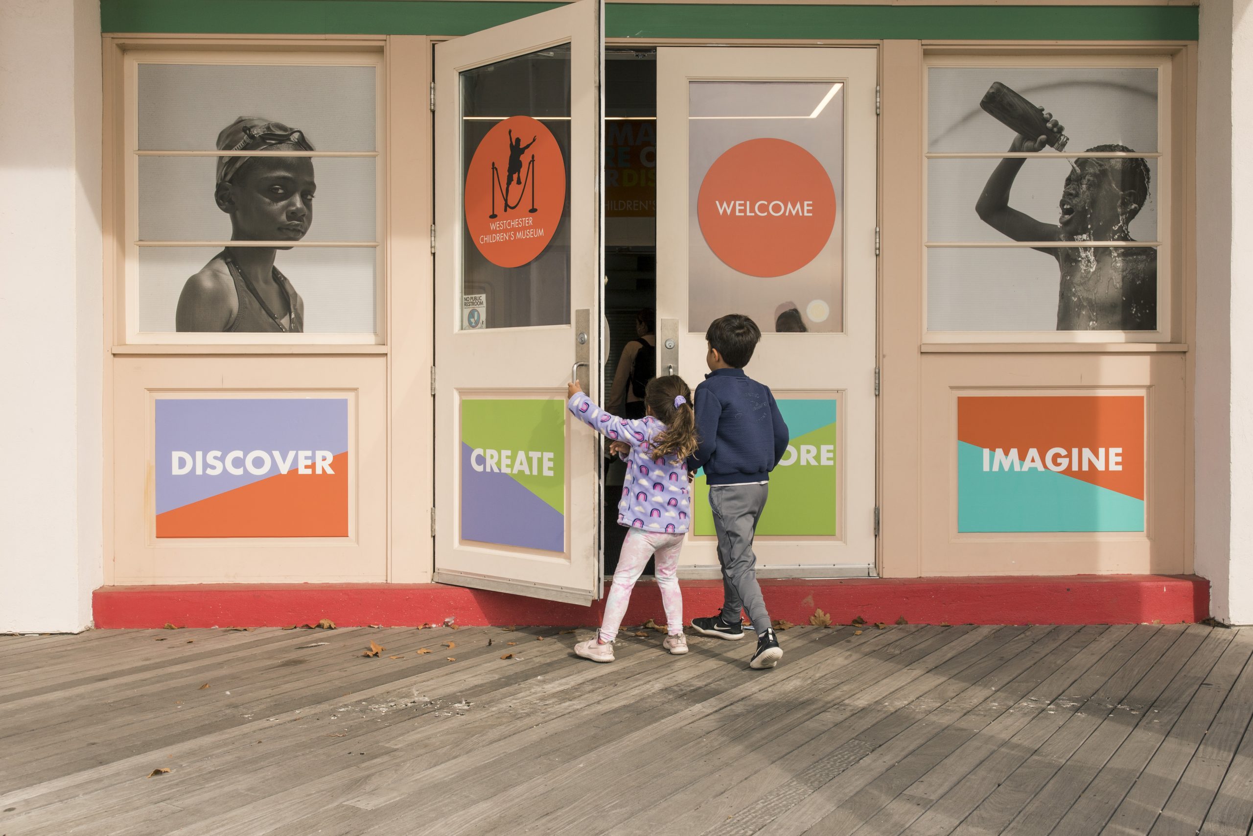 Two children pull open the door of the Westchester Children's Museum.