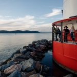 A group of people stand on the deck of the Tarrytown Lighthouse during a tour.