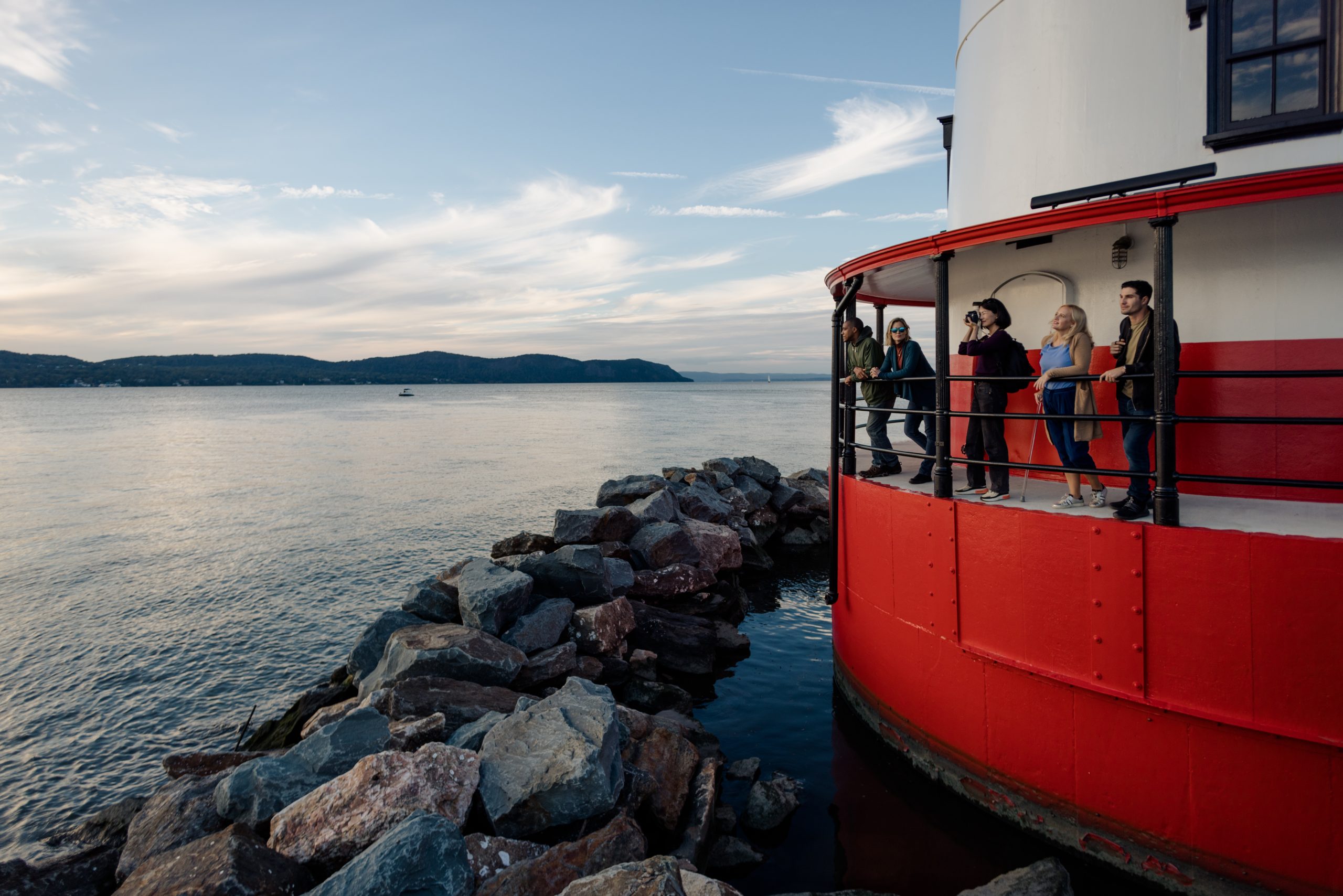 A group of people stand on the deck of the Tarrytown Lighthouse during a tour.