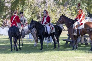 Reenactors dressed in red on horseback.