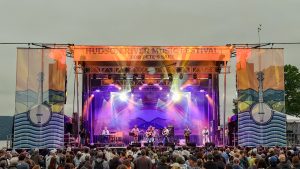 A crowd gathers in front of a stage at the Hudson River Music Festival.