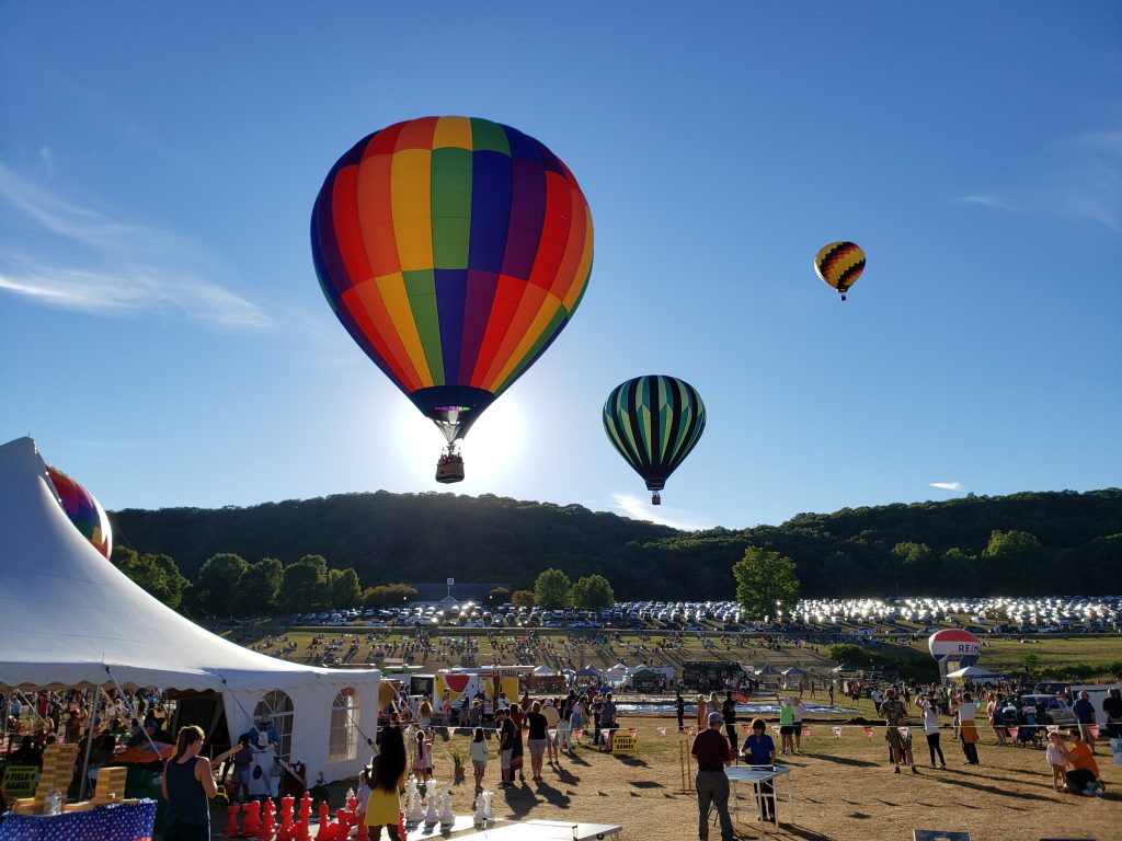colorful hot air balloons rise over hundreds of people at Tymor Park