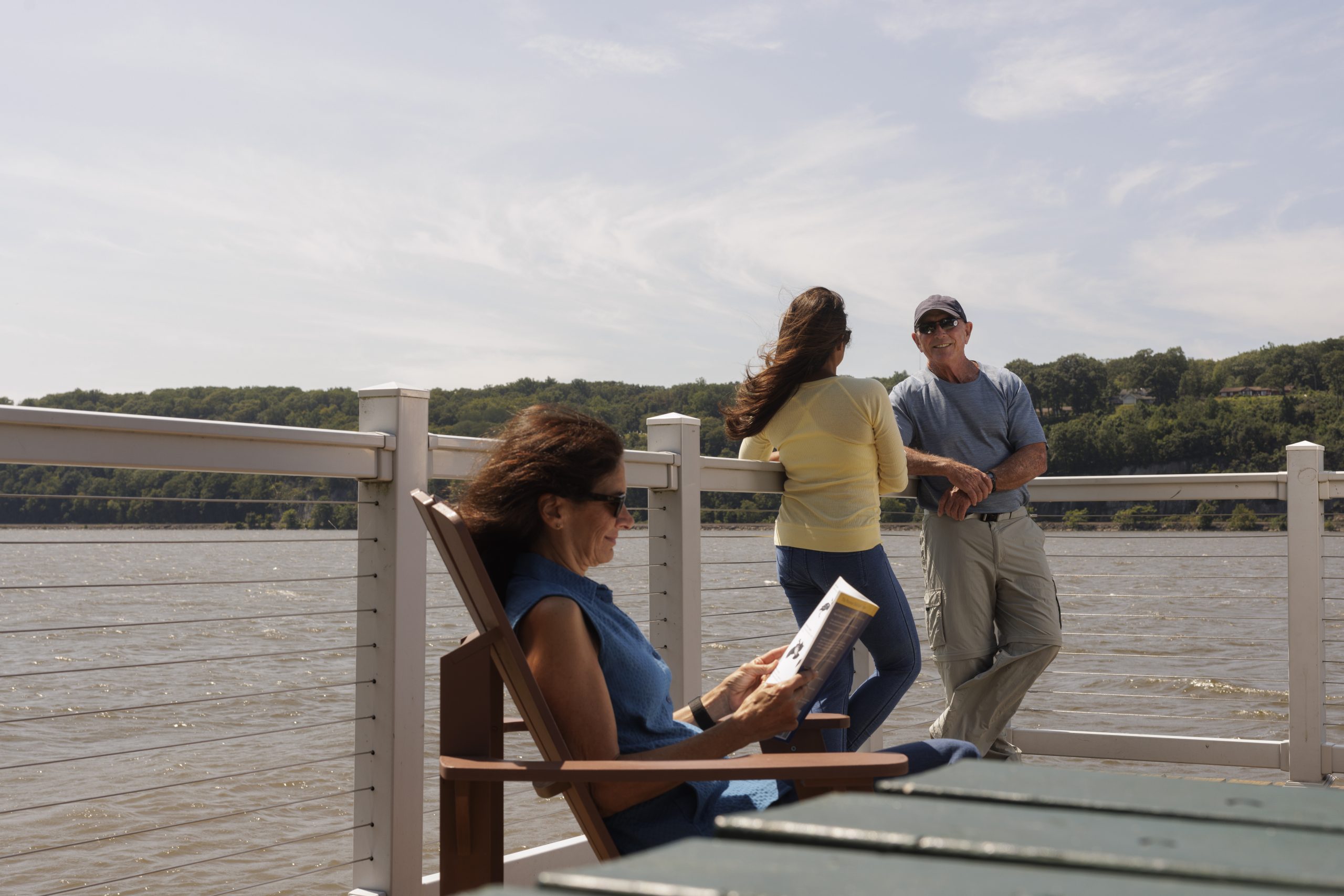 three adults stand around a platform overlooking a blue river at Quiet Cove Riverfront Park in Poughkeepsie