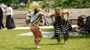 Two women dance together in the grass.