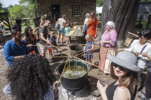 A group of people try candle dipping at Philipsburg Manor.