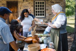 A family watches a demonstration at Philipsburg Manor.