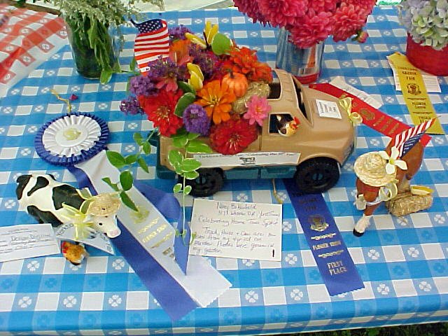 A table display with flowers and prize ribbons at the Yorktown Grange Fair.