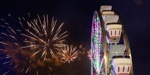 Ferris wheel overlooking fireworks in the night sky