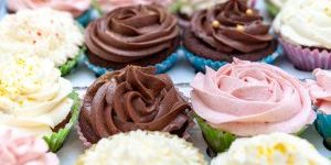 Home baked cupcakes beautifully decorated with buttercream on top placed on wooden table.